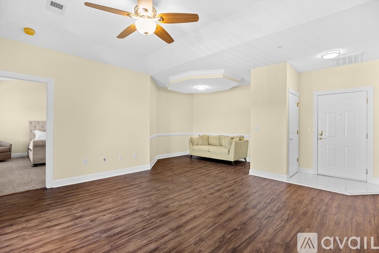 A spacious living room with a ceiling fan and hardwood flooring.