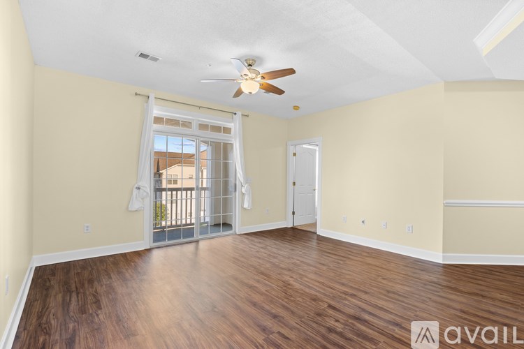 A spacious room with a ceiling fan and sliding glass doors leading to a balcony.