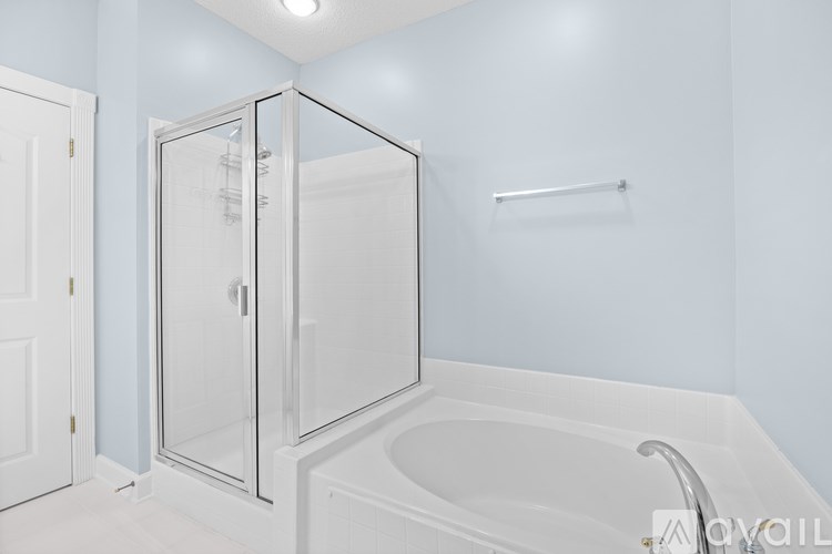 A white bathroom with a glass shower door and a white bathtub.
