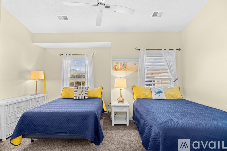 Two twin beds with blue bedspreads and yellow pillows in a room with white walls.