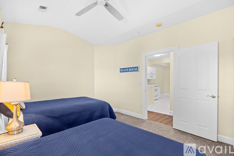 A bedroom with a bed, a lamp, and a sign that says "BEACH HOUSE".