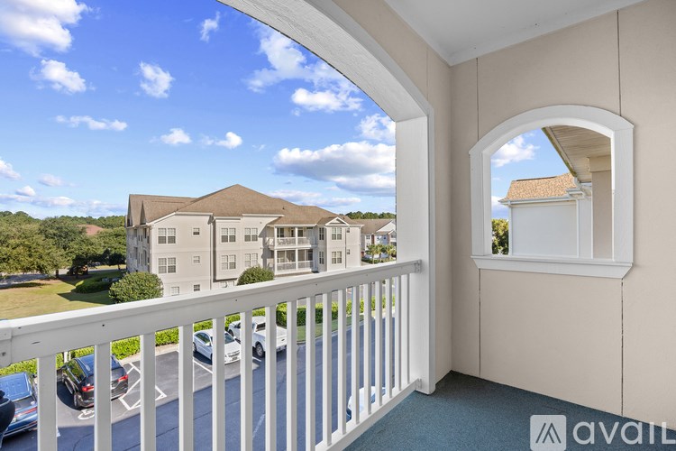 A balcony with a view of a parking lot and buildings.