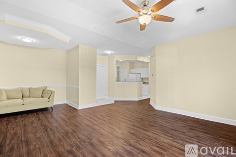 A living room with a beige sofa and a ceiling fan.