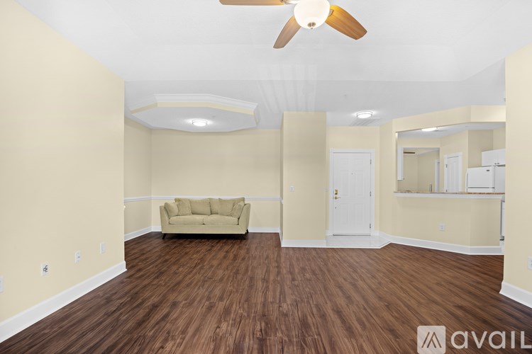 A living room with a beige couch and a ceiling fan.