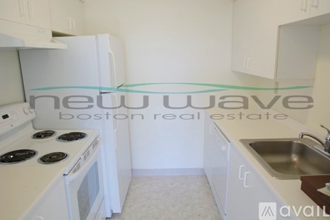 A kitchen with a white stove top oven and white cabinets.