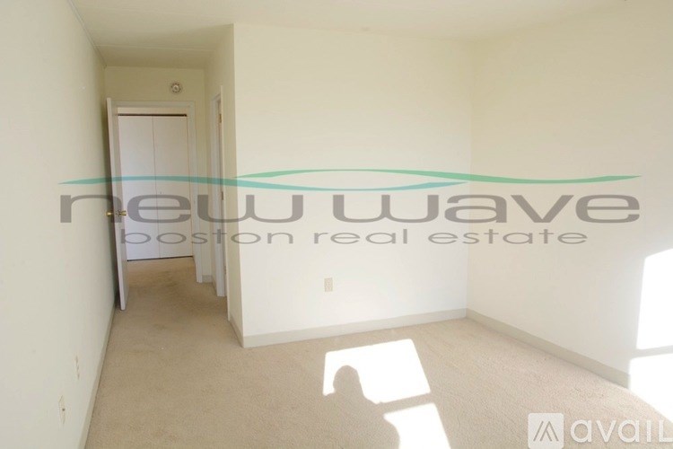 A room with a white wall and a door is available for rent.