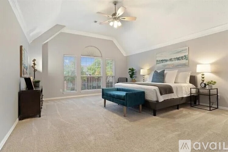 A bedroom with a large bed and a ceiling fan.