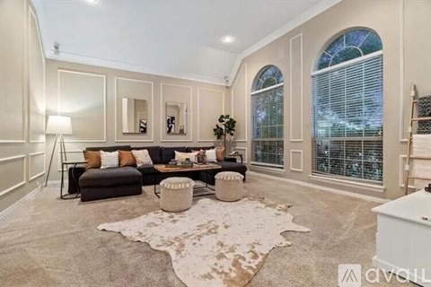 A living room with a large rug and a black couch.