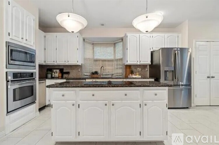 A kitchen with white cabinets and a marble countertop.