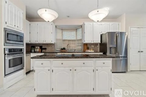 A kitchen with white cabinets and a marble countertop.
