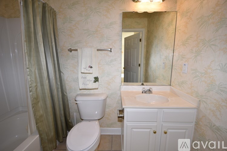 A bathroom with a toilet, sink, and mirror.