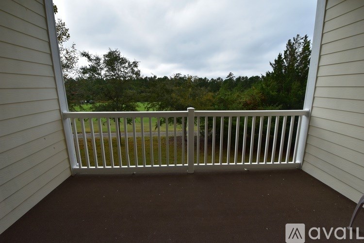 A balcony with a view of a green field and trees.