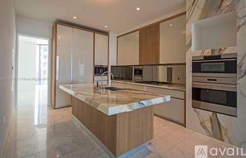 A modern kitchen with a marble countertop and stainless steel appliances.