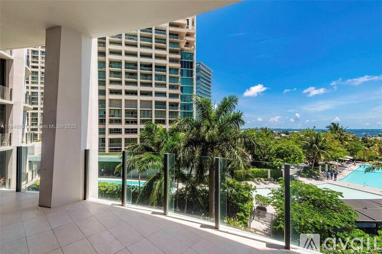 A balcony with a view of a pool and buildings.