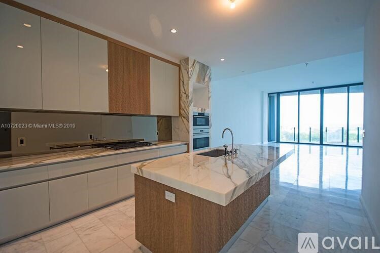A modern kitchen with a marble countertop and wooden cabinets.