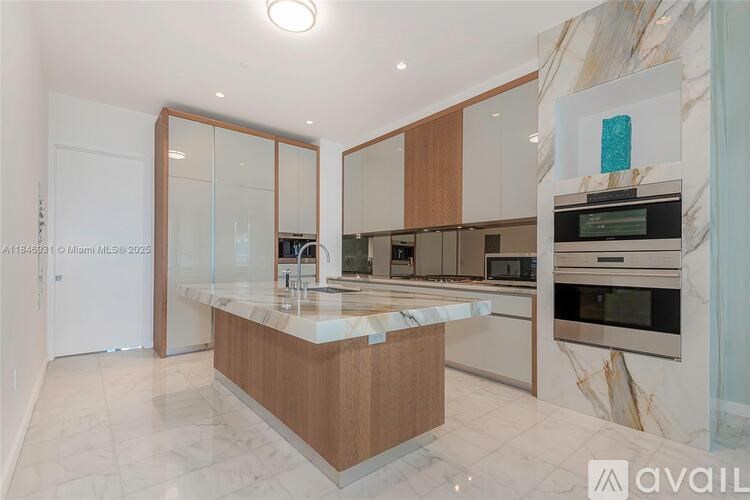 A kitchen with a marble countertop and stainless steel appliances.