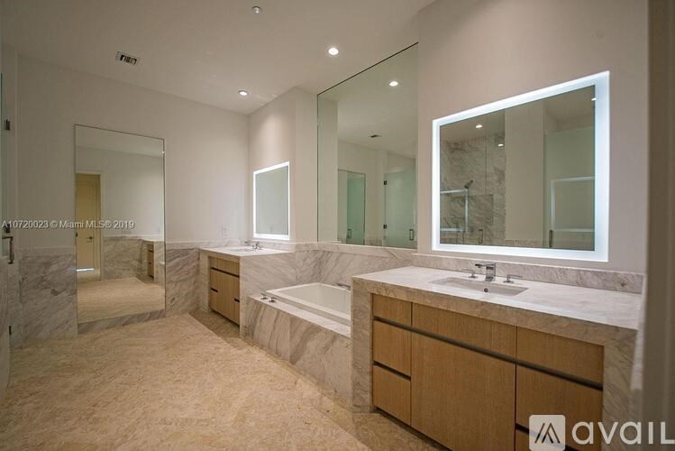 A bathroom with a marble floor and a large mirror above the sink.