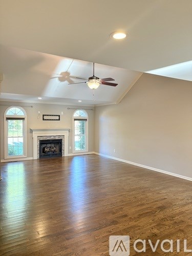 A spacious room with a fireplace and a fan on the ceiling.