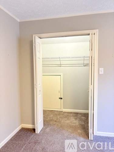 A carpeted room with an open door leading to another room.