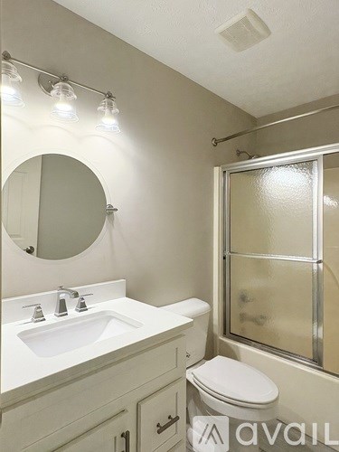 A bathroom with a sink, toilet, mirror, and shower.