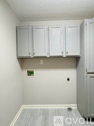 A room with white cabinets and a grey floor.