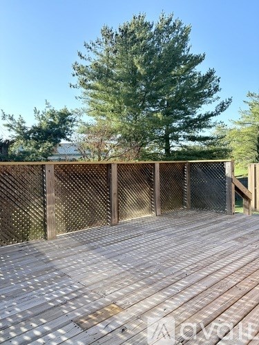 A wooden deck with a lattice fence and a tree in the background.