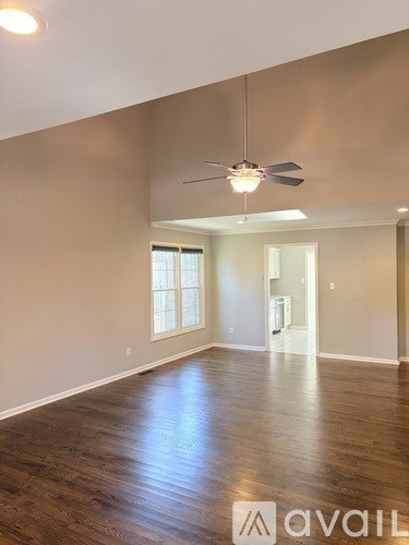 A spacious room with a ceiling fan and wooden flooring.