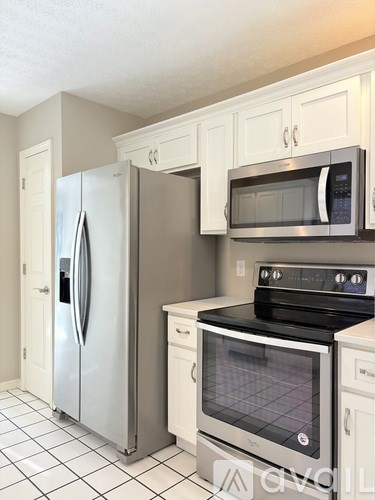 A kitchen with a stainless steel refrigerator and a black stove top oven.