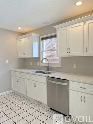 A kitchen with white cabinets and a black and white tiled floor.
