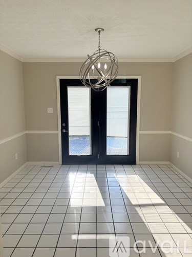 A room with a black door and a chandelier.
