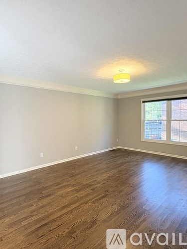 A room with wooden flooring and a window with blinds.