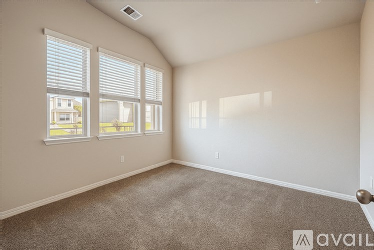 A room with a carpeted floor and a window with blinds.