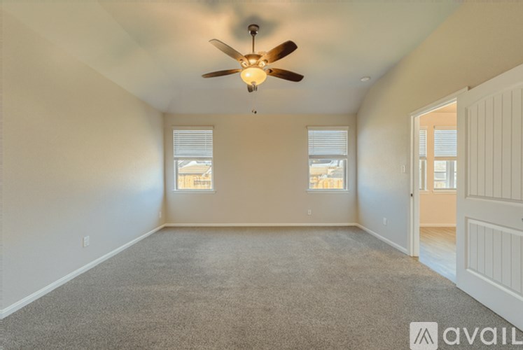 A spacious room with a ceiling fan and carpeted floor.