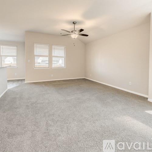 A spacious room with a ceiling fan and carpeted floor.