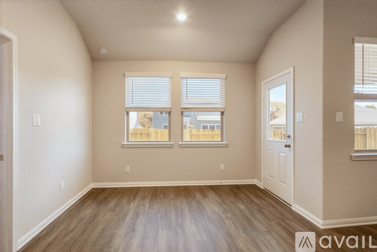 A room with wooden floors and two windows with blinds.