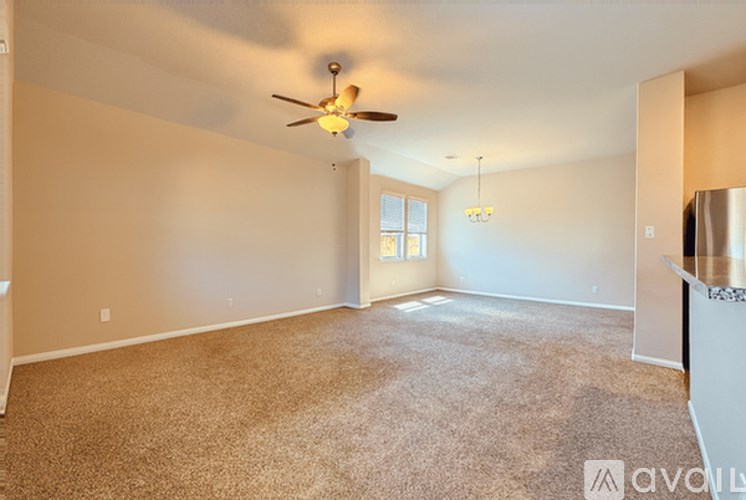 A spacious room with a ceiling fan and carpeted floor.