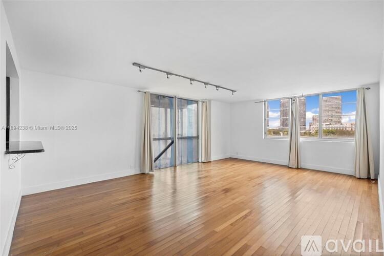 A room with wooden flooring and a large window overlooking a cityscape.