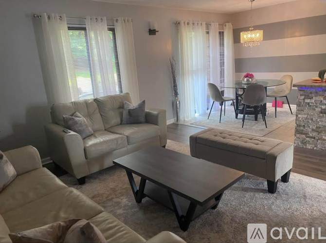 A living room with a white couch, a coffee table, and a dining table with chairs.