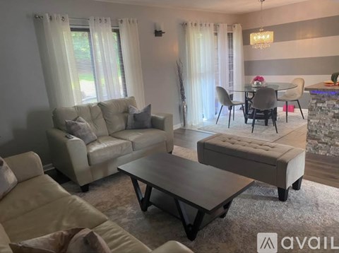 A living room with a white couch, a coffee table, and a dining table with chairs.