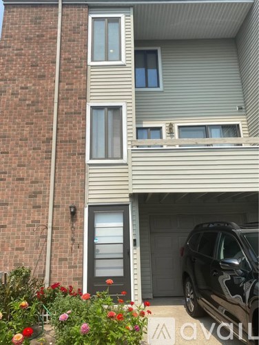 A black car is parked in the garage of a two-story house.