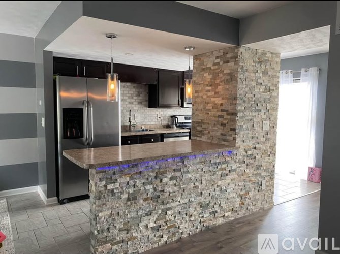 A modern kitchen with a stone barrier and a refrigerator.