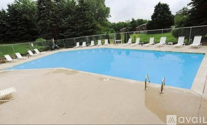 A pool surrounded by chairs and trees.