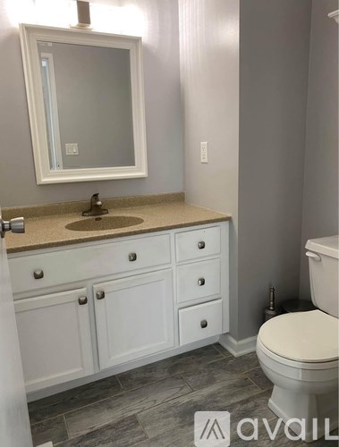 A bathroom with a white toilet, sink, and cabinets.