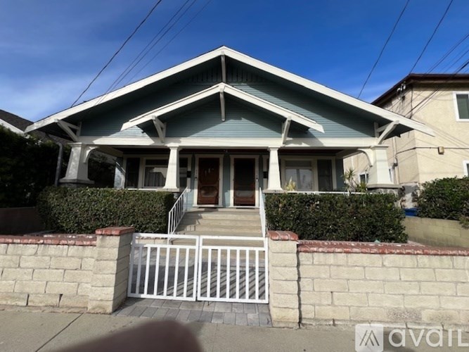 A house with a blue roof and a white fence in front.