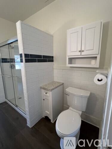 A white toilet sits in a bathroom with a white cabinet above it.