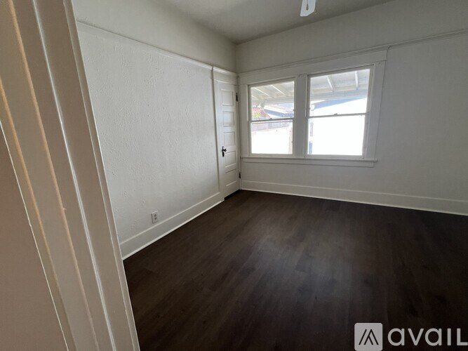 A room with wooden flooring and a window with blinds.