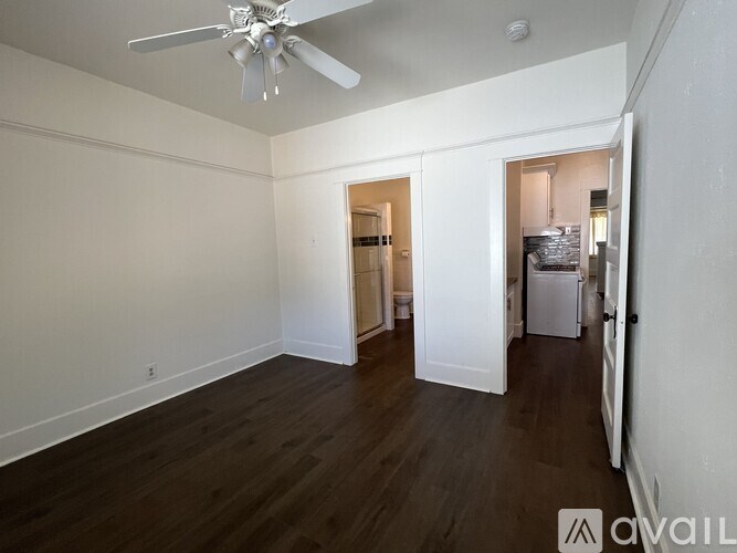 A room with a ceiling fan and wooden floors.