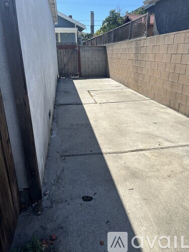 A narrow alley with a wooden fence on the left and a brick wall on the right.