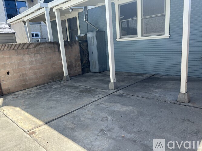 A patio area with a concrete floor and a wall with a brick pattern.