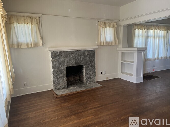A living room with a stone fireplace and wooden floors.